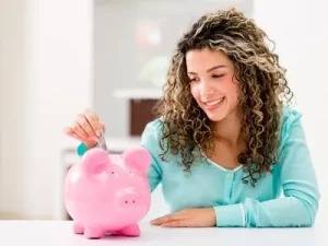 A girl inserting a money into her piggy bank