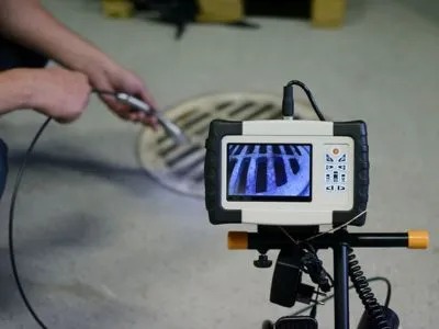 A person uses an inspection camera to examine a drain.