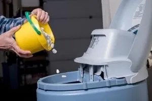 A person refills a water softener tank.